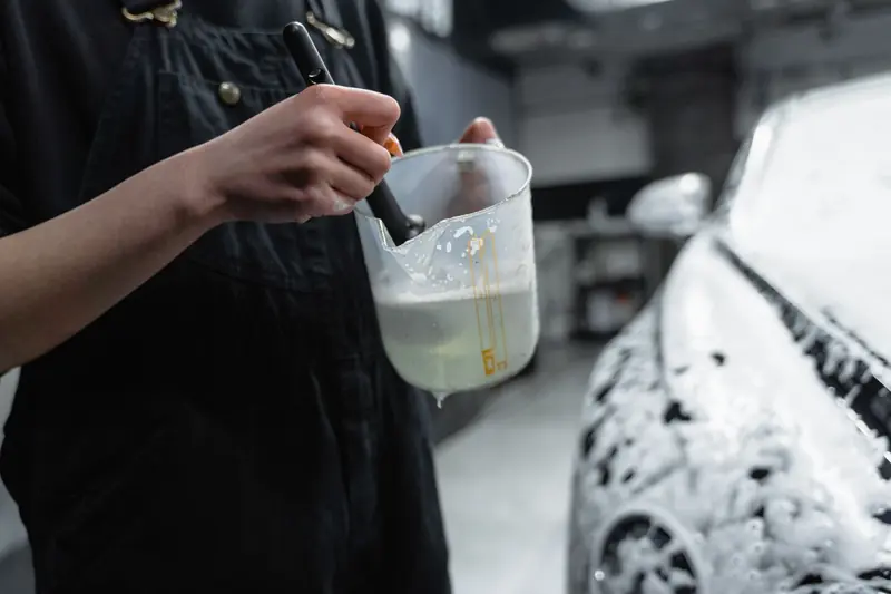 Close-up of person using brush and soap for car detailing in a garage