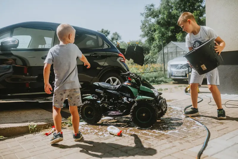 Two kids wash a toy car with soap and water on a sunny day. Fun and playful activity