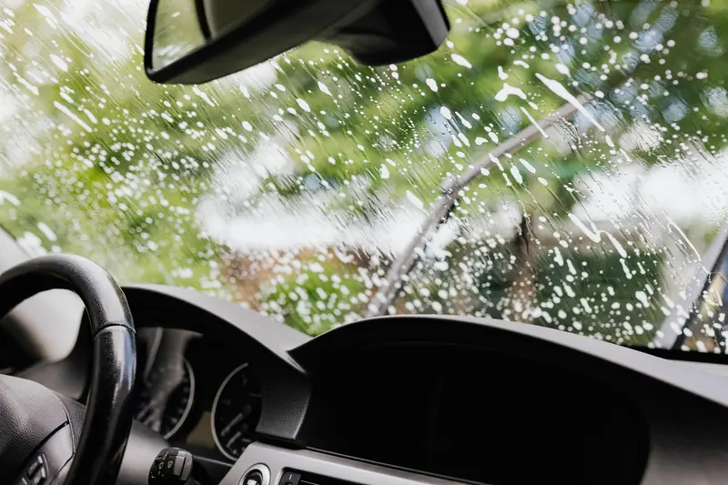 Interior view of a car with soapy windshield during cleaning. Clear dashboard visible