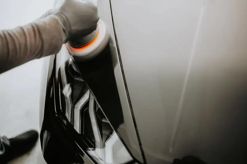 Close-up view of a person polishing a black car using a buffing machine